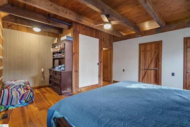 bedroom with beam ceiling, ceiling fan, wooden ceiling, wood walls, and light hardwood / wood-style floors