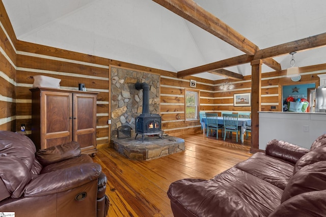 living room featuring a wood stove, light hardwood / wood-style floors, and vaulted ceiling with beams