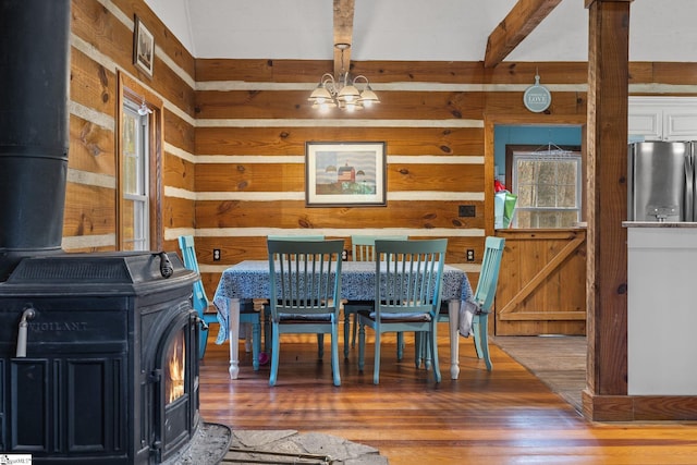 dining space with a chandelier, dark hardwood / wood-style flooring, a wood stove, and wooden walls