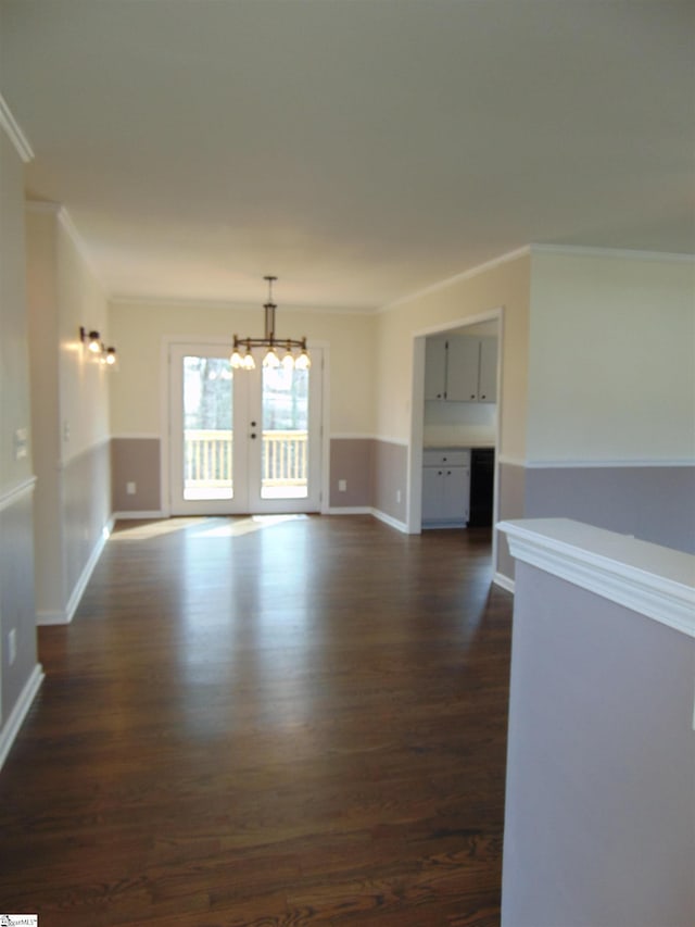 spare room featuring dark hardwood / wood-style flooring, crown molding, french doors, and an inviting chandelier