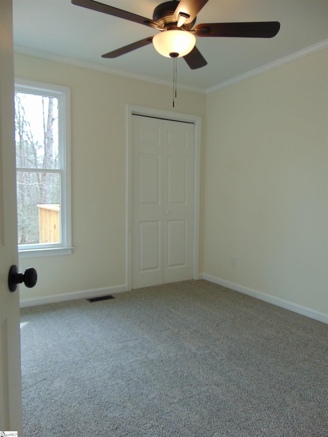 unfurnished bedroom featuring carpet flooring, crown molding, a closet, and ceiling fan