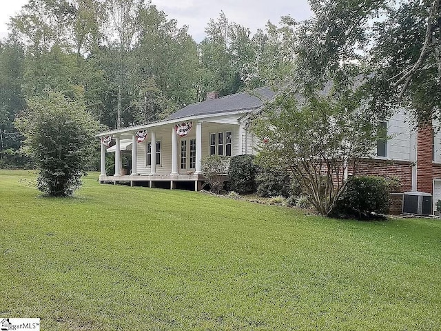 view of front of house with covered porch, a front yard, and central AC