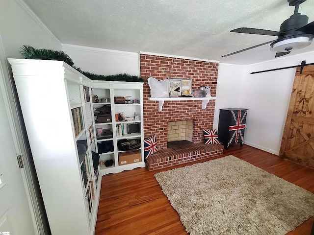 living room with a textured ceiling, ceiling fan, dark wood-type flooring, and a brick fireplace