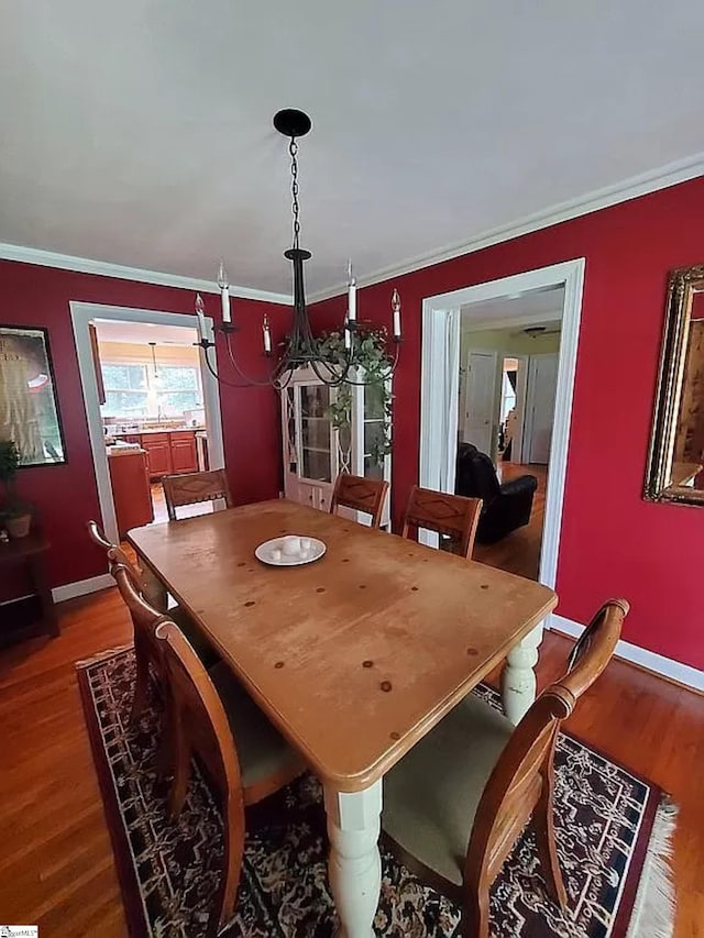 dining area featuring hardwood / wood-style floors, an inviting chandelier, and ornamental molding