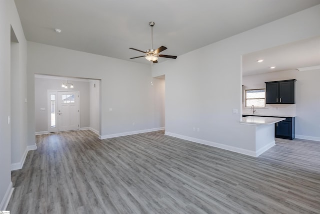 unfurnished living room with ceiling fan, light wood finished floors, plenty of natural light, and baseboards