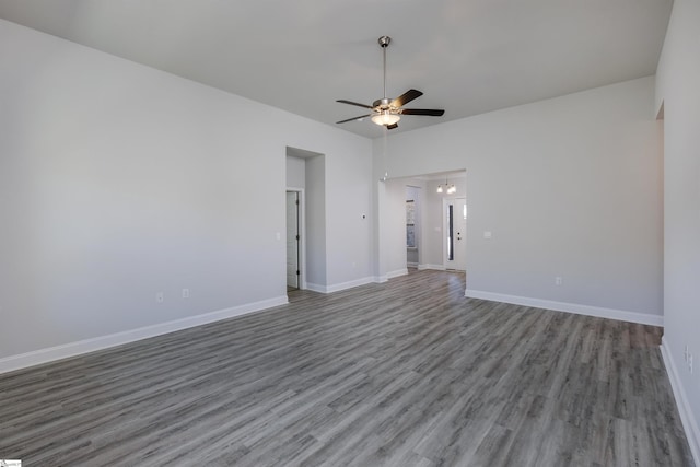 empty room with wood finished floors, a ceiling fan, and baseboards