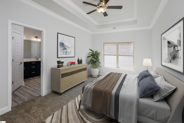 bedroom featuring carpet, crown molding, a raised ceiling, ensuite bathroom, and baseboards