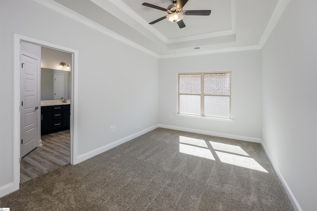 unfurnished bedroom featuring visible vents, baseboards, a raised ceiling, dark colored carpet, and crown molding