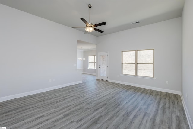 spare room with light wood-type flooring, baseboards, visible vents, and ceiling fan with notable chandelier