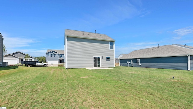 back of property with central AC and a lawn