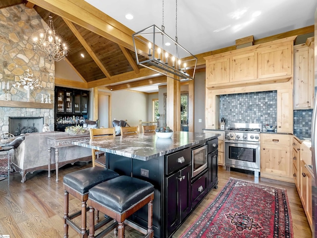 kitchen featuring light brown cabinetry, backsplash, appliances with stainless steel finishes, a breakfast bar, and a kitchen island