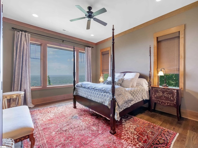 bedroom with ceiling fan, dark hardwood / wood-style flooring, and a water view