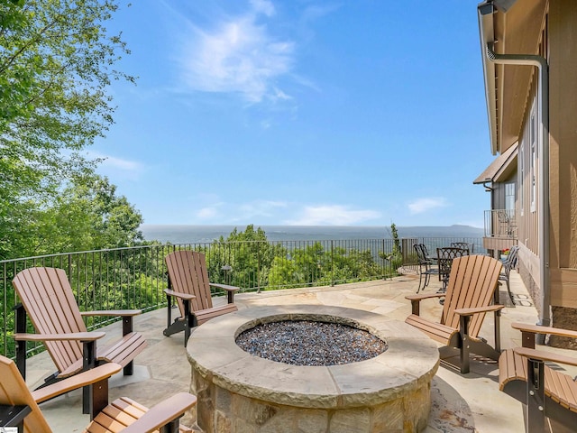 view of patio with a fire pit and a water view