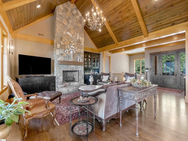 living room with beam ceiling, a stone fireplace, high vaulted ceiling, and wooden ceiling