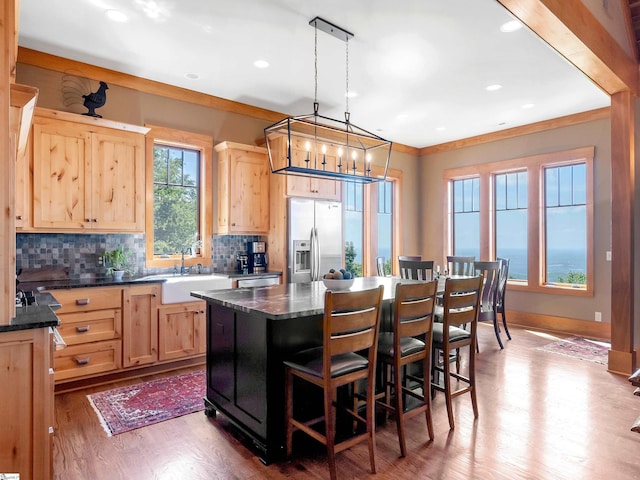 kitchen featuring pendant lighting, a center island, sink, light brown cabinetry, and stainless steel appliances