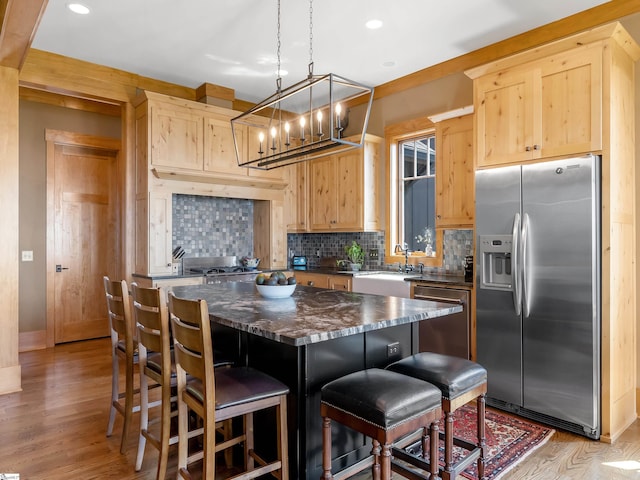 kitchen featuring light brown cabinets, sink, light hardwood / wood-style floors, a kitchen island, and stainless steel appliances