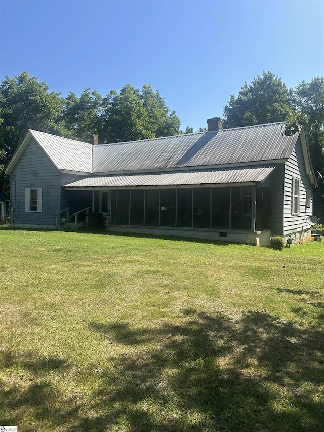 back of house with a sunroom and a lawn