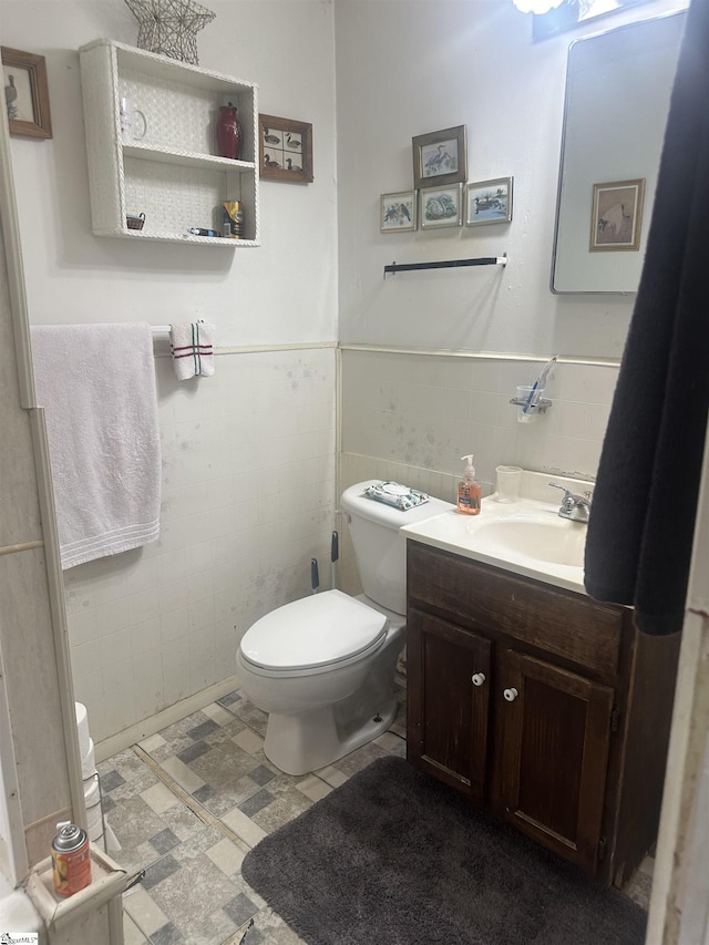 bathroom with vanity, toilet, and tile walls