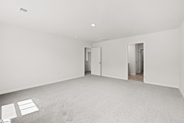 unfurnished bedroom with a walk in closet and light carpet