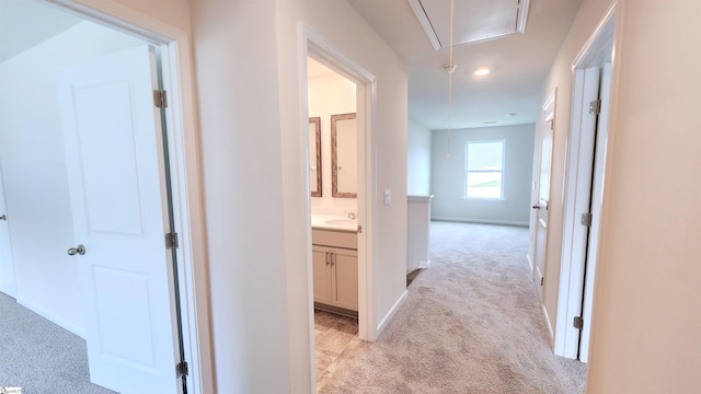 corridor featuring light carpet and sink