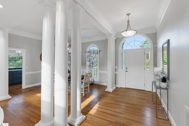 foyer entrance with ornate columns, crown molding, and hardwood / wood-style flooring