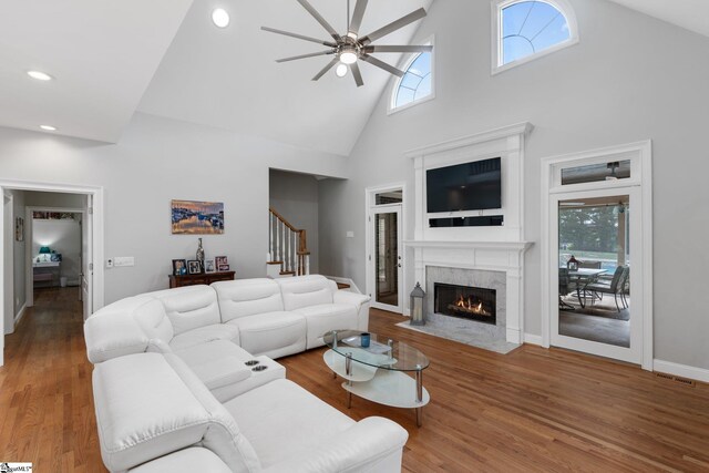 living room with hardwood / wood-style flooring, high vaulted ceiling, a premium fireplace, and ceiling fan