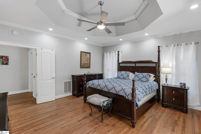 bedroom with crown molding, a tray ceiling, light hardwood / wood-style flooring, and ceiling fan