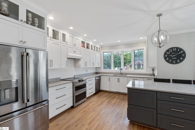 kitchen with crown molding, appliances with stainless steel finishes, pendant lighting, light stone countertops, and white cabinets