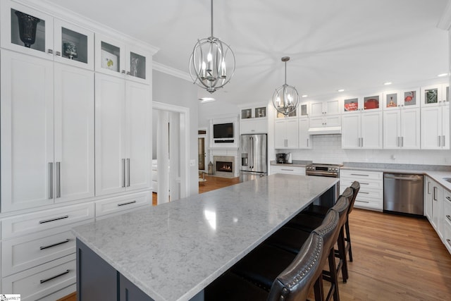 kitchen featuring a spacious island, white cabinetry, stainless steel appliances, and decorative light fixtures