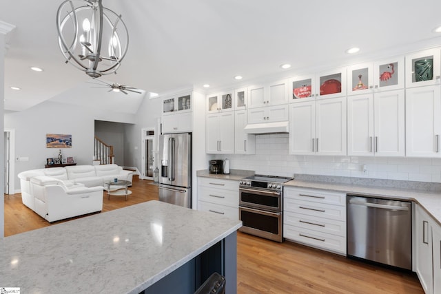 kitchen with lofted ceiling, white cabinetry, appliances with stainless steel finishes, pendant lighting, and light hardwood / wood-style floors