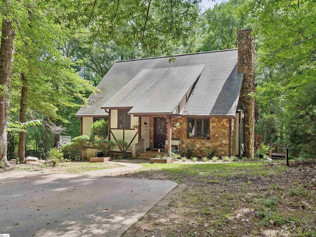 view of front of house with stone siding and a chimney