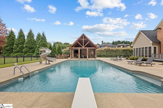 view of pool with a diving board, a patio area, a fireplace, and a water slide