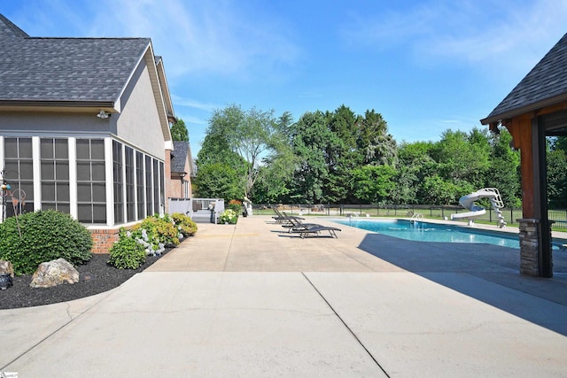 view of swimming pool with a water slide and a patio