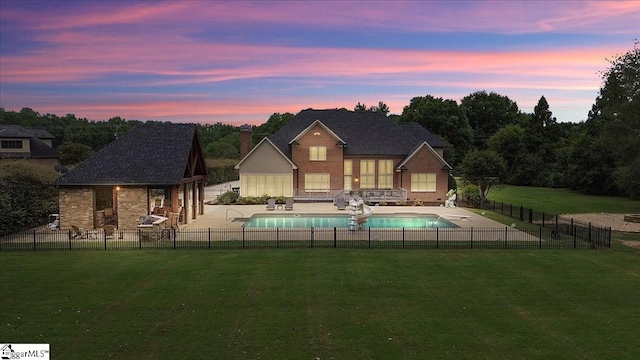 pool at dusk featuring a lawn and a patio