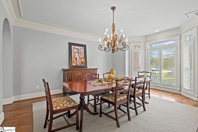 dining space with crown molding, hardwood / wood-style floors, and a chandelier