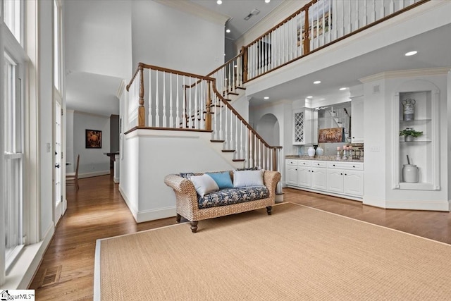 entryway featuring hardwood / wood-style flooring, a towering ceiling, and ornamental molding