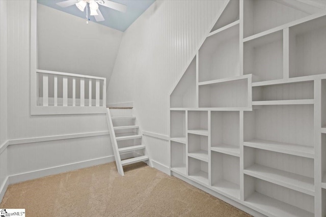 spacious closet with ceiling fan, carpet floors, and lofted ceiling