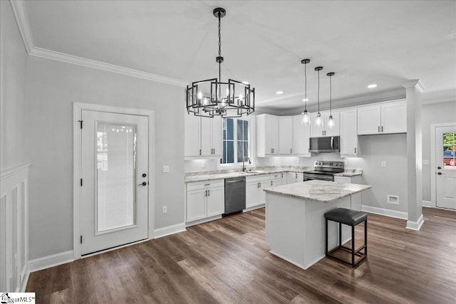 kitchen with sink, appliances with stainless steel finishes, white cabinetry, hanging light fixtures, and a kitchen island