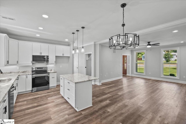 kitchen with appliances with stainless steel finishes, decorative light fixtures, a kitchen island, and white cabinets