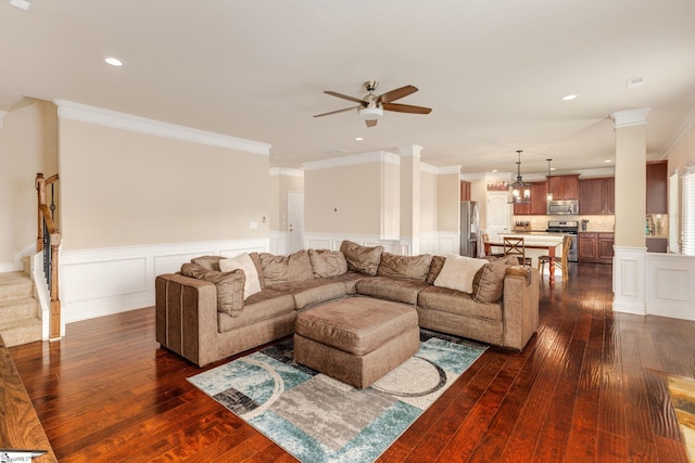 living room with ornate columns, crown molding, dark hardwood / wood-style flooring, and ceiling fan with notable chandelier