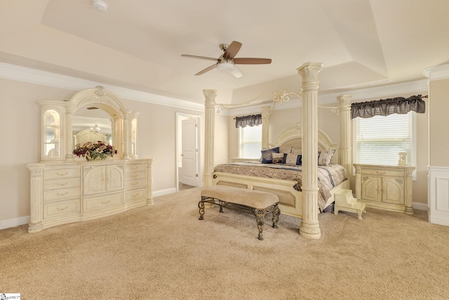 bedroom with a raised ceiling, ceiling fan, decorative columns, and light colored carpet