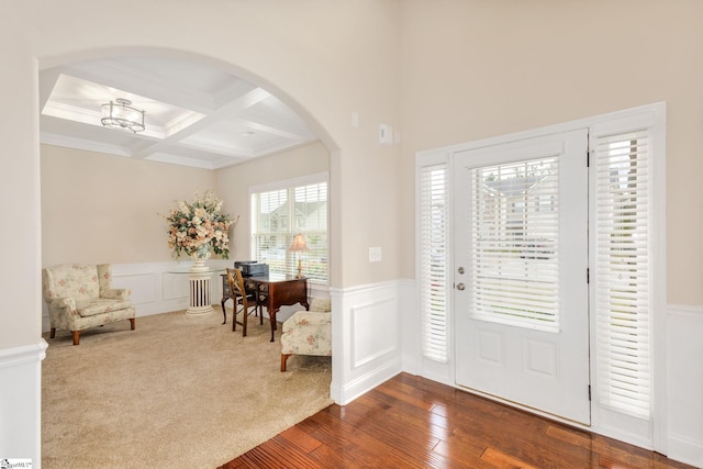 carpeted entrance foyer with beamed ceiling, ornamental molding, an inviting chandelier, and coffered ceiling