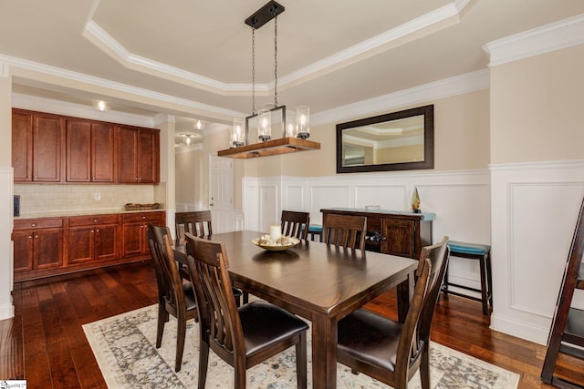 dining room with a raised ceiling, dark hardwood / wood-style flooring, a notable chandelier, and ornamental molding