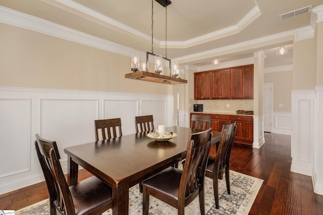 dining area featuring dark hardwood / wood-style floors, a raised ceiling, crown molding, and a notable chandelier