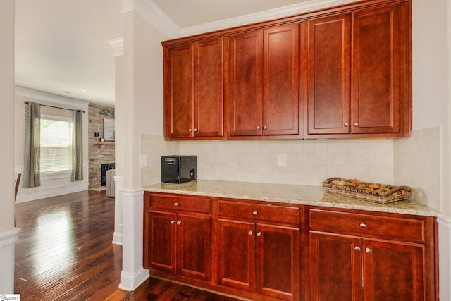 kitchen with backsplash, a stone fireplace, crown molding, dark hardwood / wood-style floors, and light stone counters