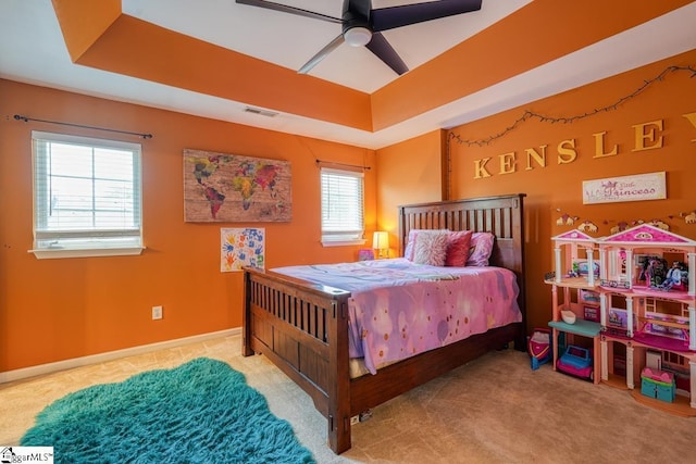 bedroom with a raised ceiling, multiple windows, and ceiling fan