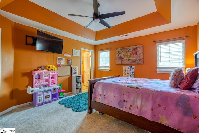 bedroom with a tray ceiling, multiple windows, and ceiling fan