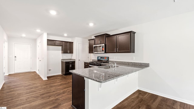 kitchen with dark hardwood / wood-style flooring, black range with gas stovetop, dark brown cabinetry, sink, and stone countertops