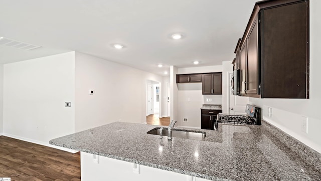 kitchen featuring kitchen peninsula, range, stone countertops, and sink