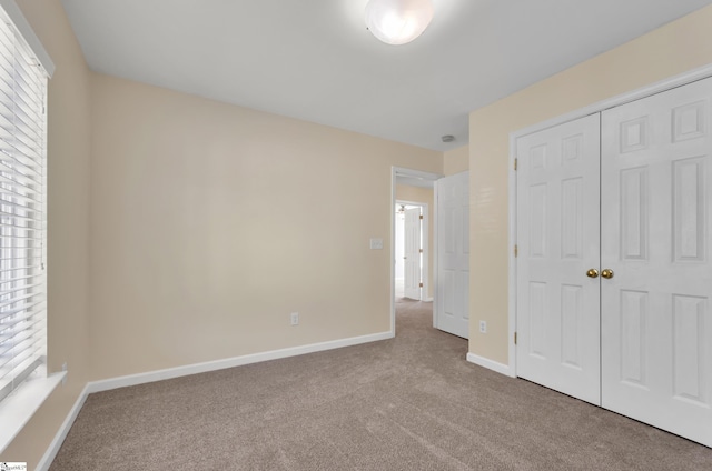 unfurnished bedroom featuring light colored carpet and a closet